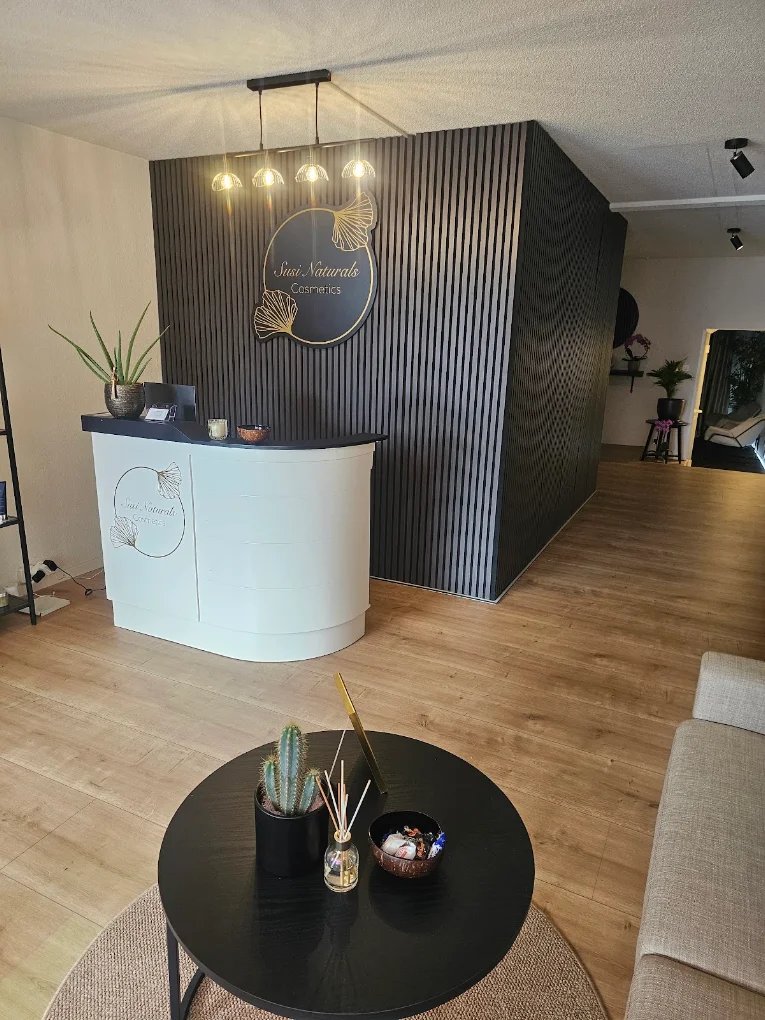 Empfangsbereich des Studios mit goldenem Logo an der dunklen Holzwand